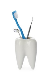 Photo of Tooth shaped holder with dentist's tools and brush on white background