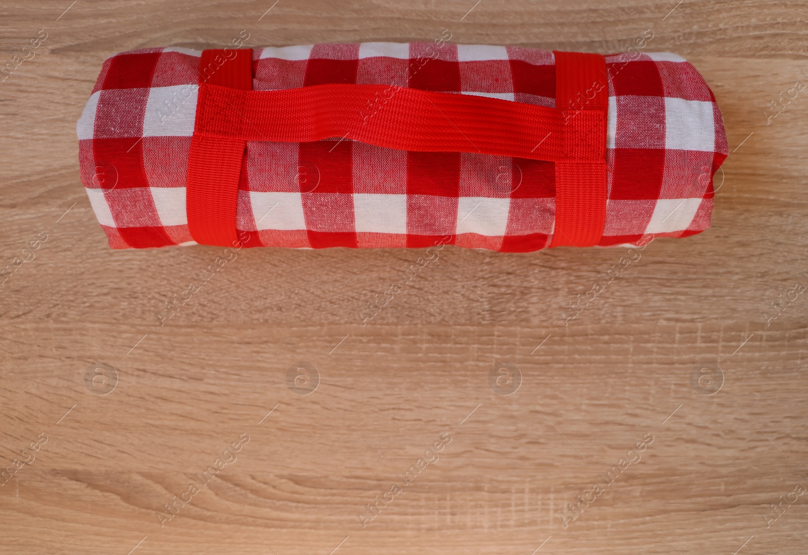 Photo of Folded checkered picnic blanket on wooden table, top view. Space for text