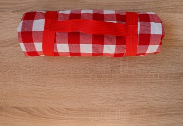 Photo of Folded checkered picnic blanket on wooden table, top view. Space for text