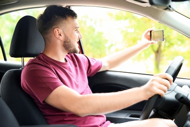 Happy young man taking selfie in car