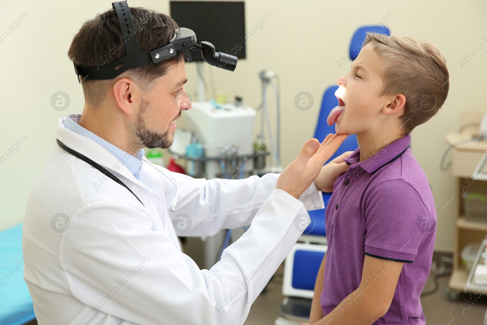 Photo of Male otolaryngologist examining little child in hospital