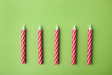 Photo of Red striped birthday candles on green background, top view
