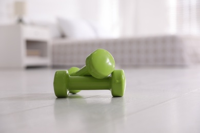 Photo of Green dumbbells on floor in room. Home fitness