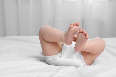 Photo of Little baby in diaper lying on bed indoors, closeup