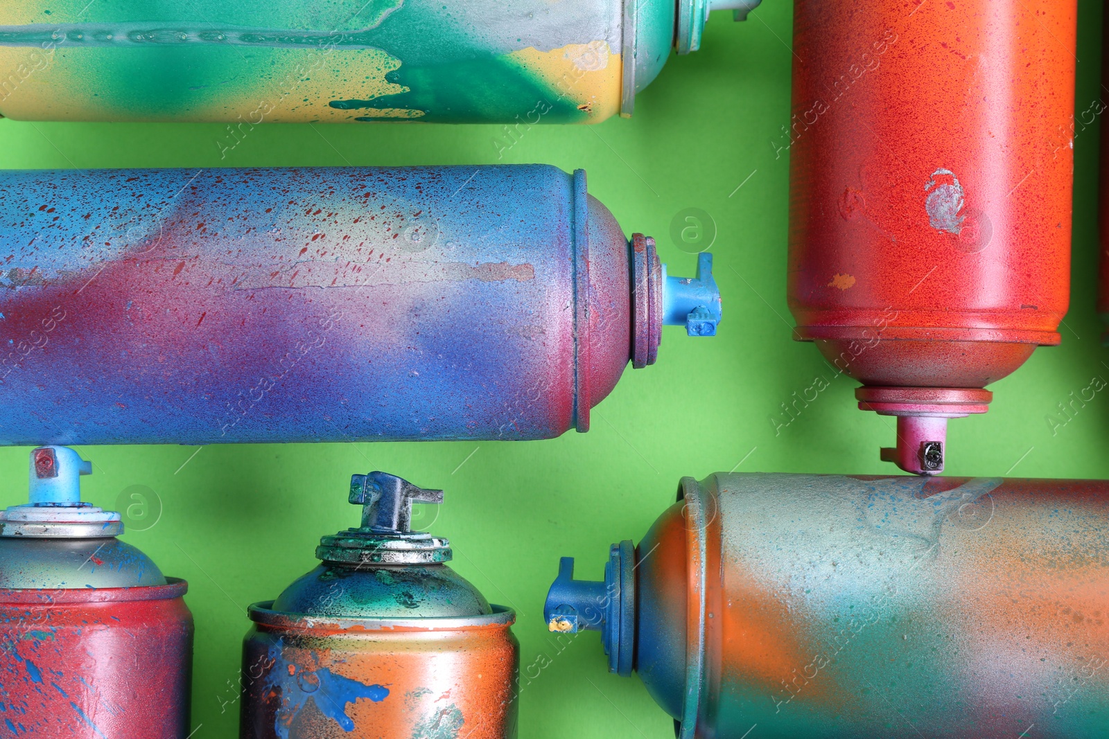 Photo of Many spray paint cans on green background, flat lay