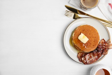 Delicious pancakes with maple syrup, butter and fried bacon on white wooden table, flat lay. Space for text