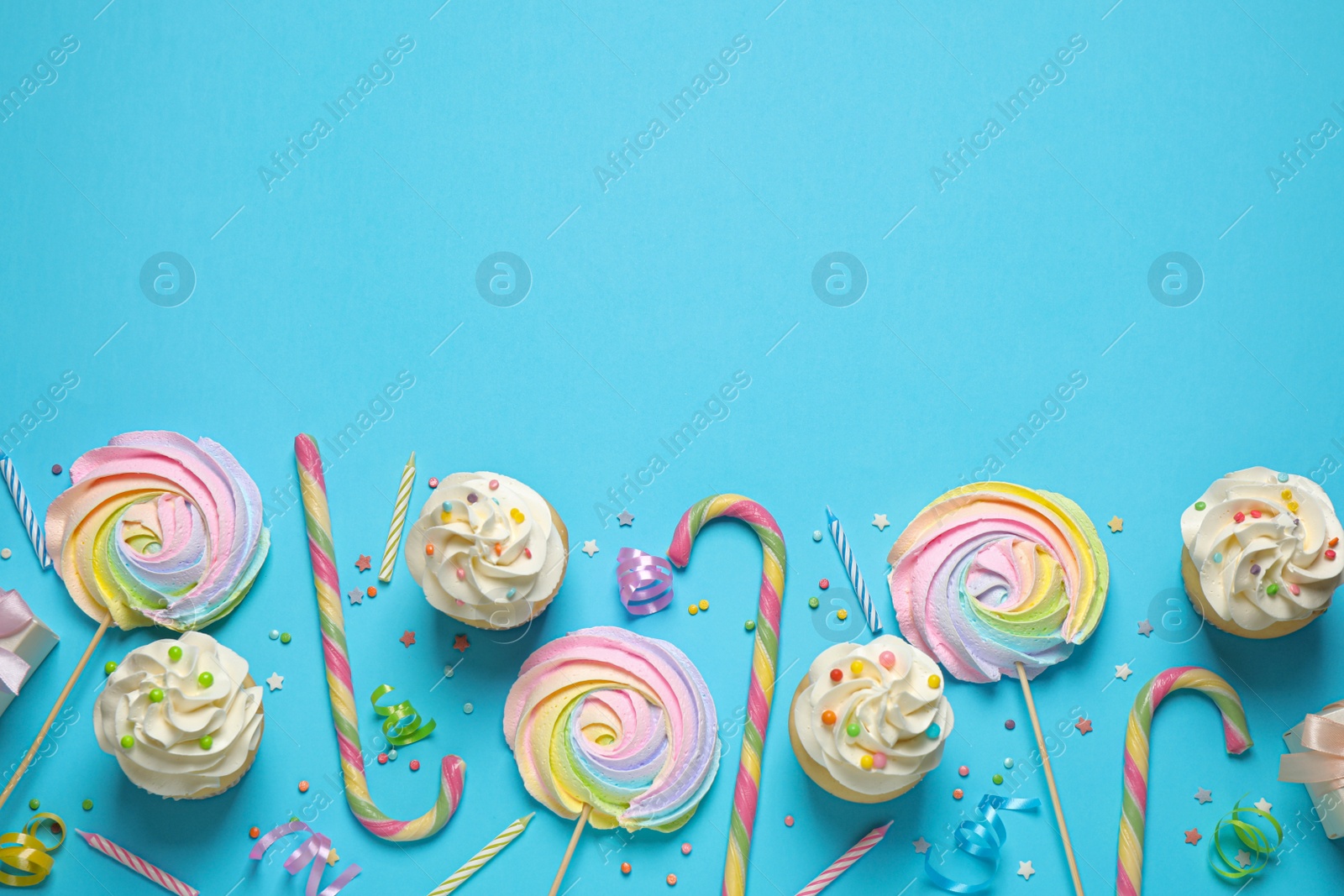 Photo of Flat lay composition with cupcakes on light blue background, space for text. Birthday party