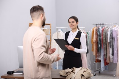 Dry-cleaning service. Happy woman working with client indoors