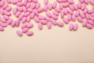 Photo of Many pink dragee candies on yellow background, flat lay. Space for text