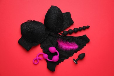 Photo of Sex toys and lingerie on red background, flat lay