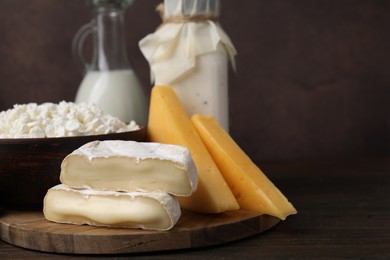 Photo of Dairy products. Different kinds of cheese and milk on wooden table, space for text