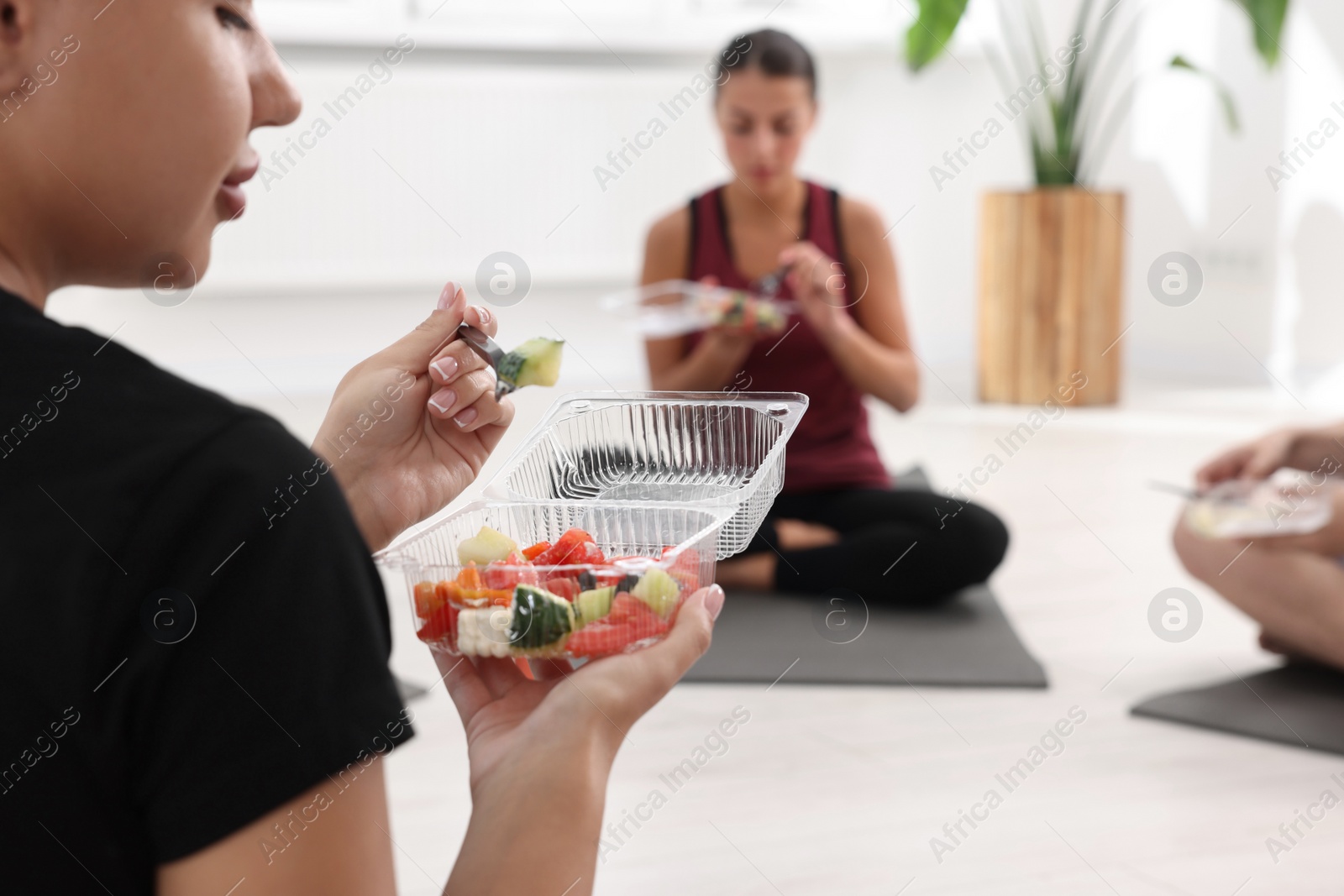 Photo of Group of people eating healthy food after yoga class indoors, closeup. Space for text