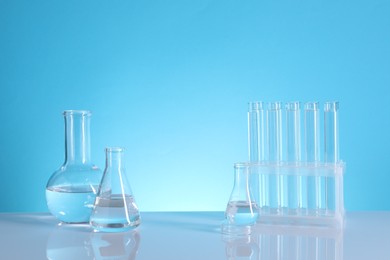 Photo of Laboratory analysis. Glass test tubes and flasks on table against light blue background