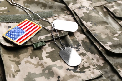Photo of Military ID tags and US army flag patch on camouflage uniform