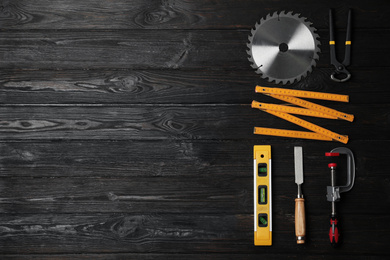 Photo of Flat lay composition with carpenter's tools on black wooden background. Space for text