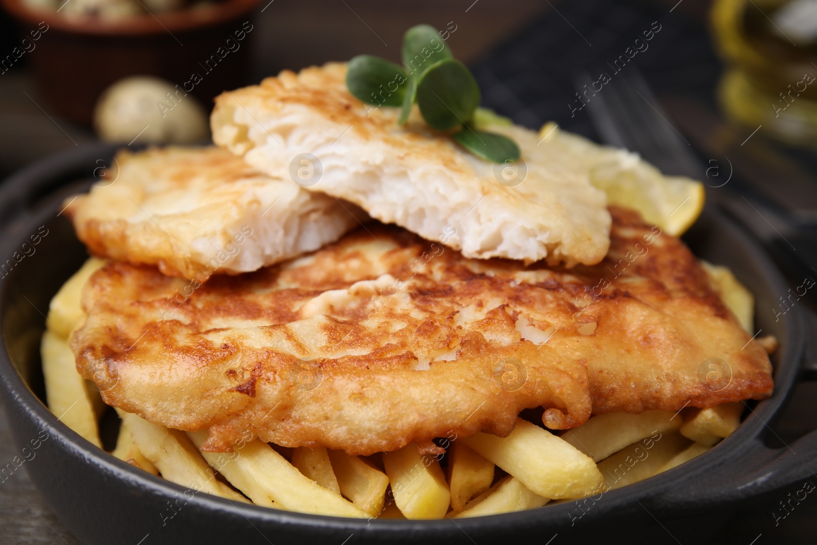 Photo of Tasty soda water battered fish and potato chips in serving pan, closeup