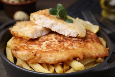Photo of Tasty soda water battered fish and potato chips in serving pan, closeup