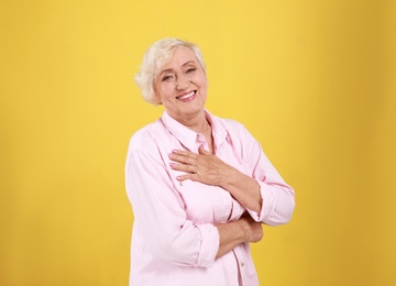 Emotional senior woman in casual outfit on yellow background