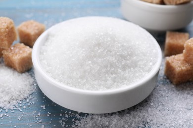 Different types of sugar on light blue wooden table, closeup