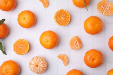 Photo of Fresh juicy tangerines on white tiled table, flat lay