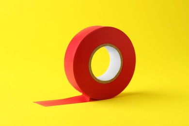 Photo of Red insulating tape on yellow background. Electrician's supply