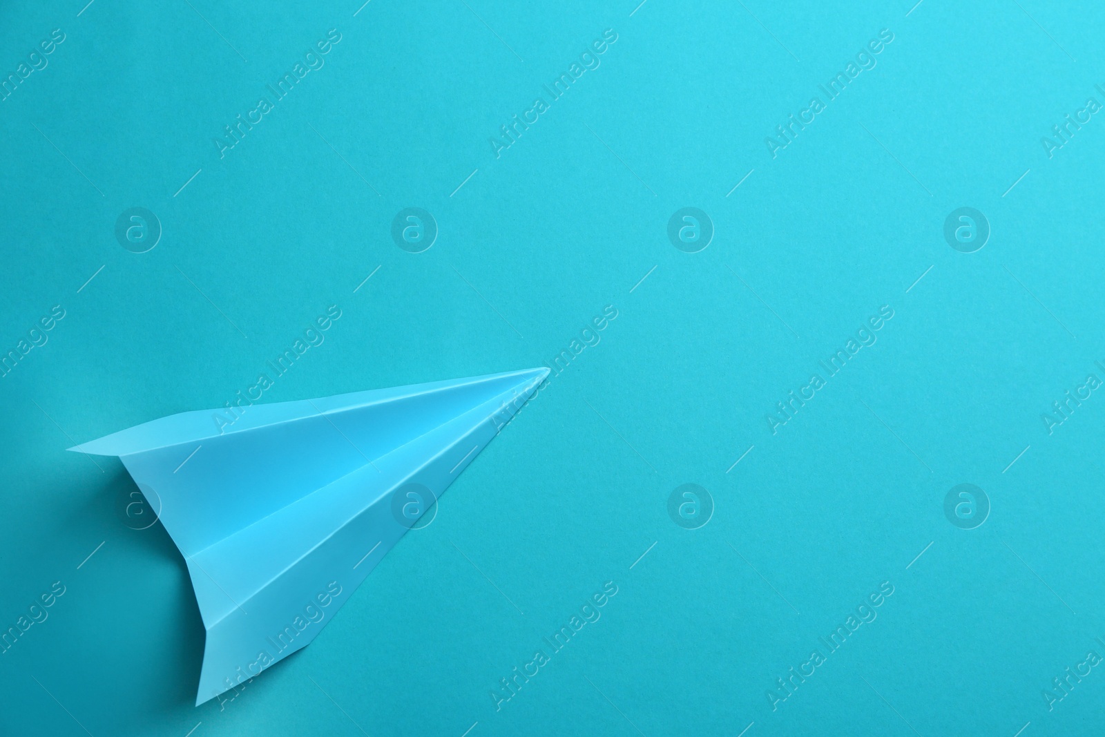 Photo of Paper plane on light blue background, top view. Space for text