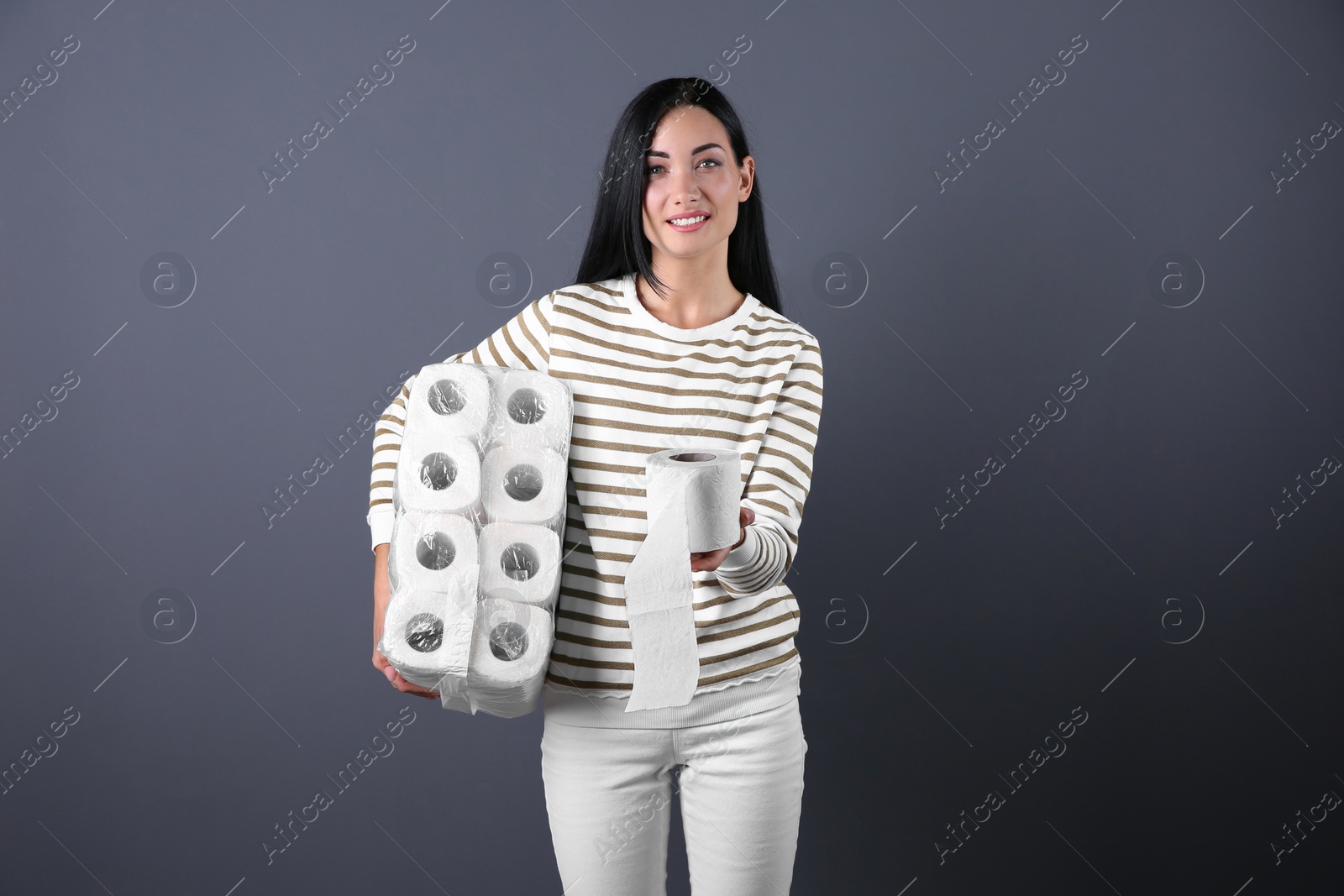 Photo of Beautiful woman holding toilet paper rolls on color background