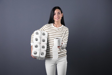 Photo of Beautiful woman holding toilet paper rolls on color background