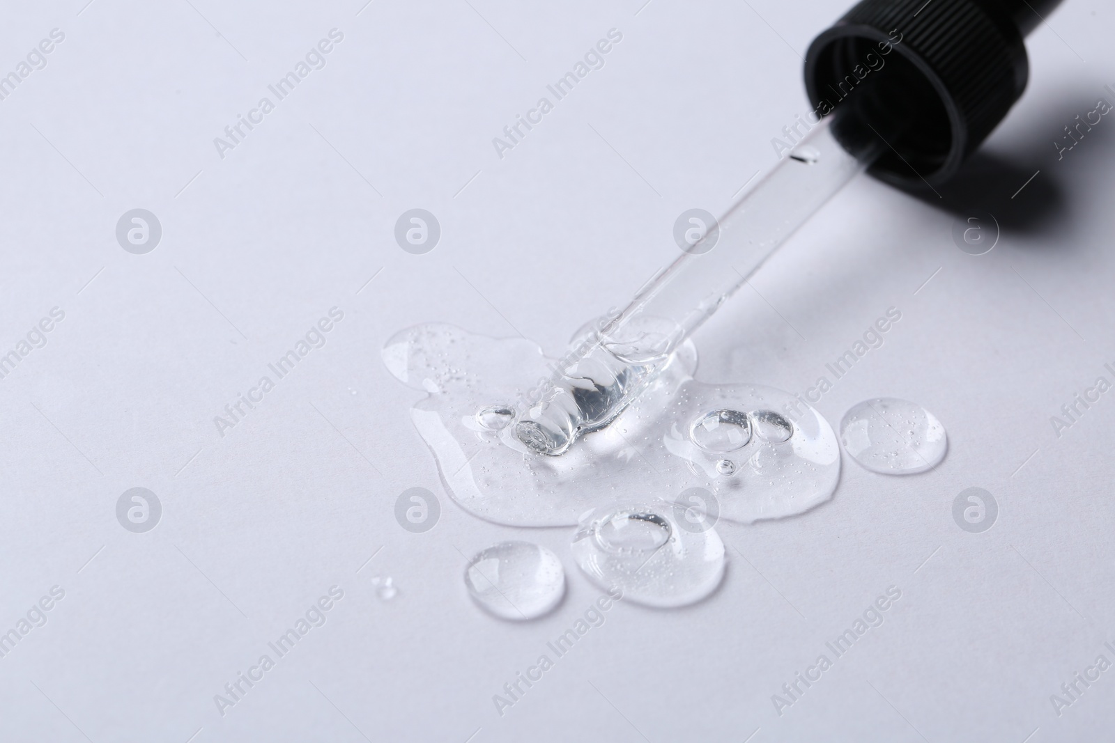 Photo of Pipette with cosmetic serum on white background, space for text