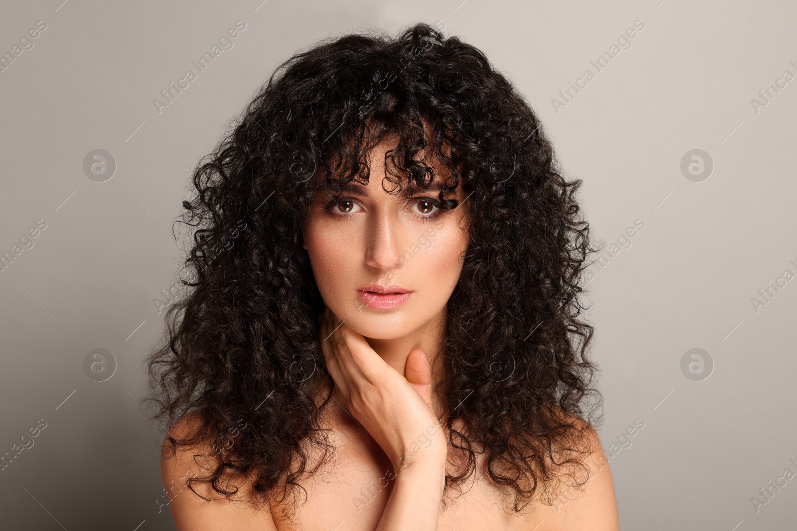 Photo of Beautiful young woman with long curly hair on light grey background