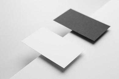 Photo of Blank black and white business cards on light background. Mockup for design