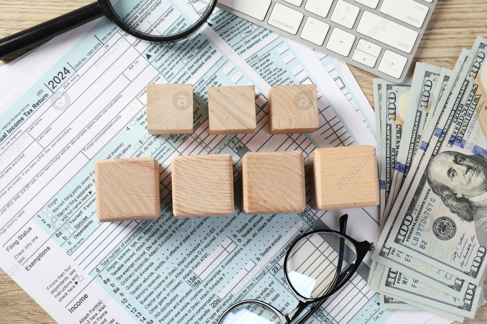 Photo of Taxes. Cubes, money, glasses and documents on light wooden table, flat lay