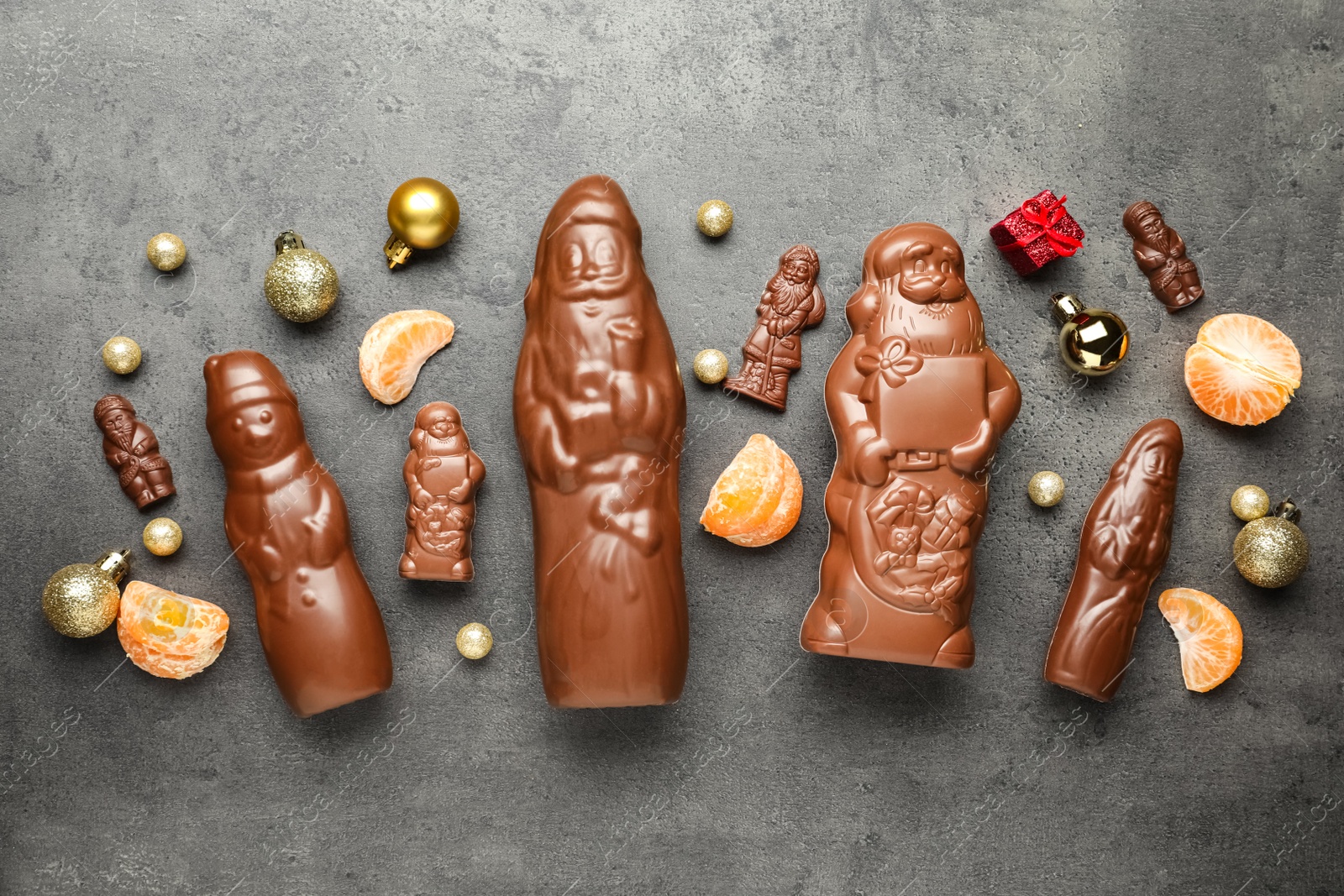 Photo of Flat lay composition with chocolate Santa Claus candies on grey table