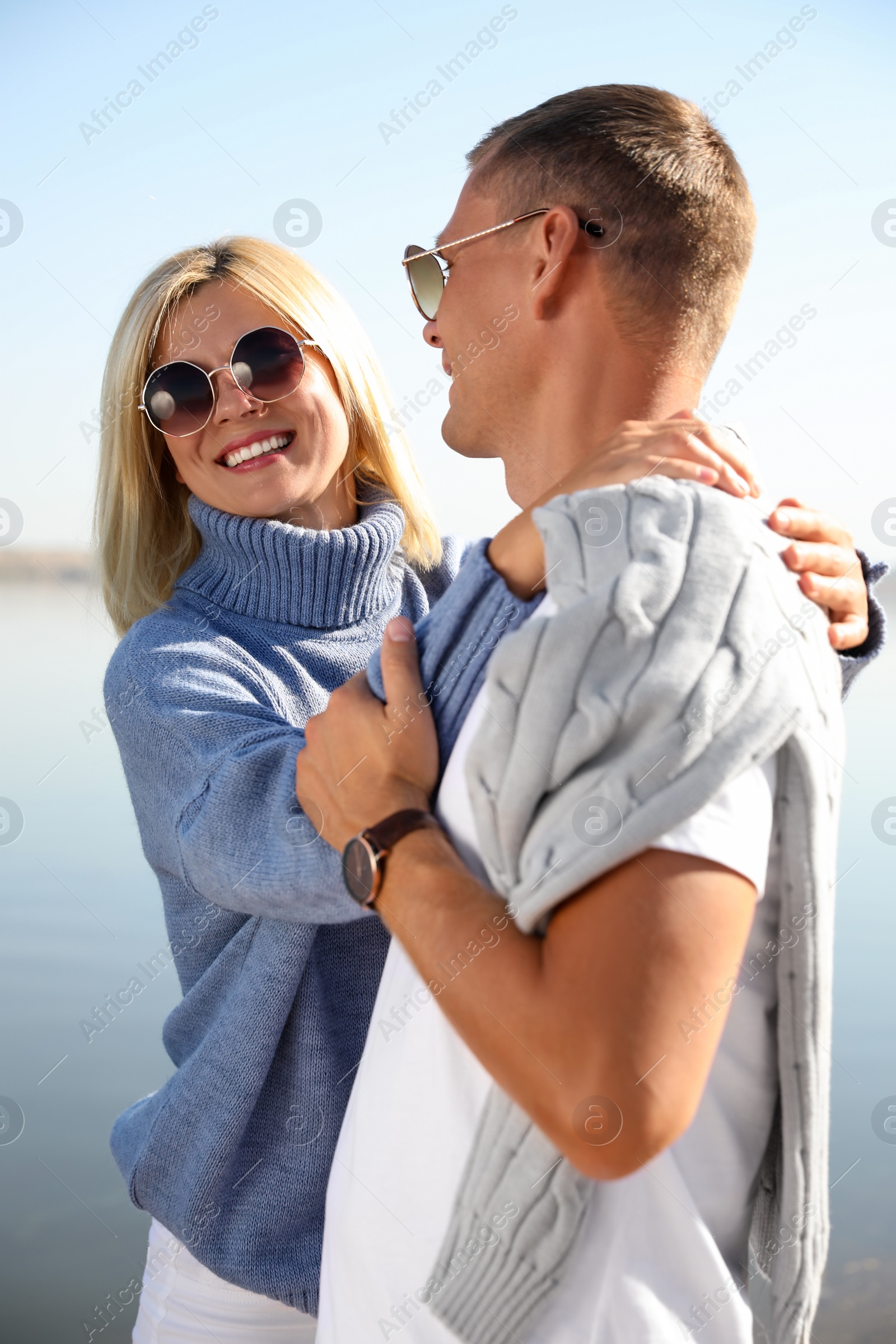 Photo of Happy couple in stylish sweaters outdoors on sunny day
