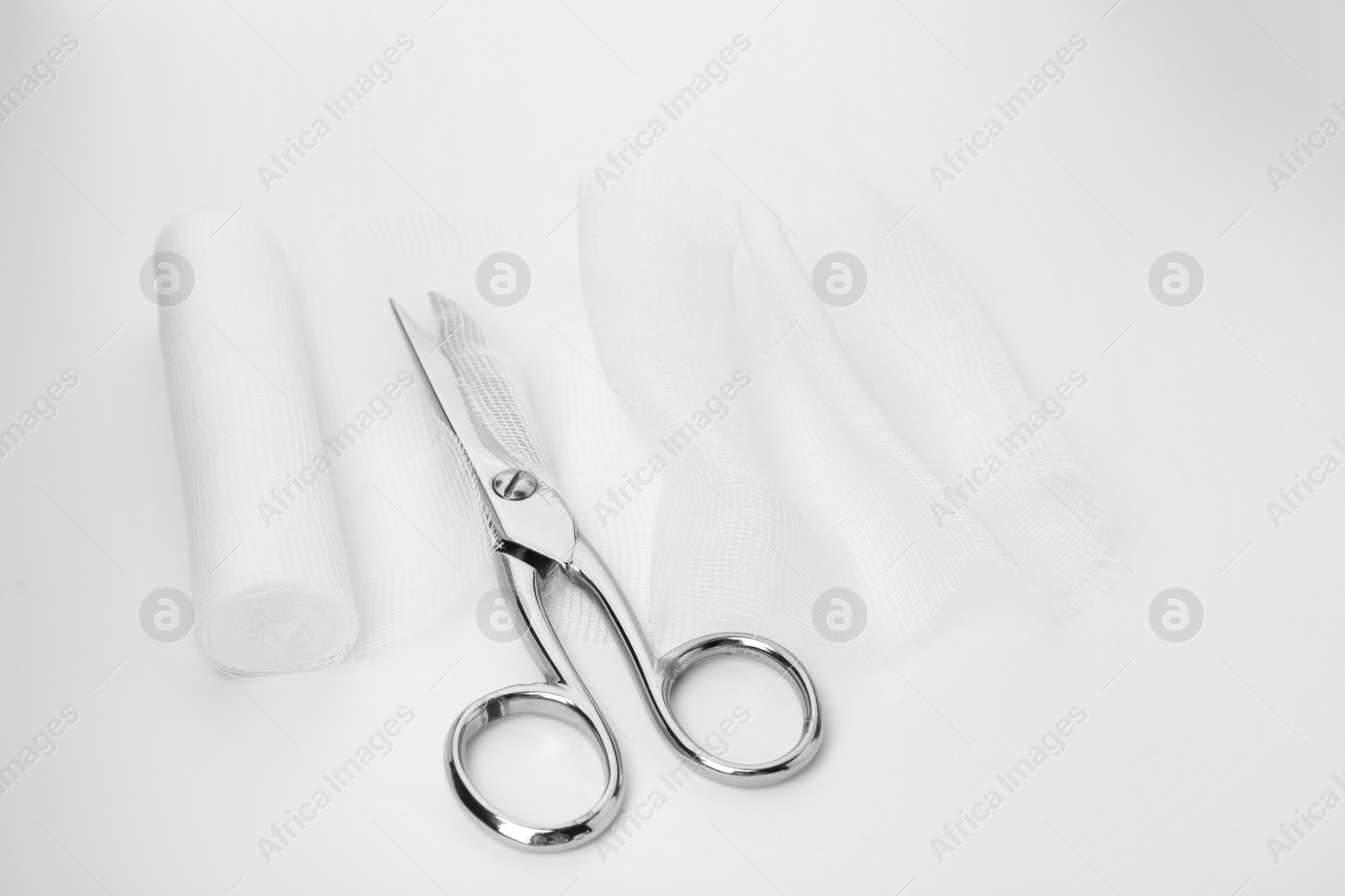 Photo of Medical cotton bandage and scissors on white background