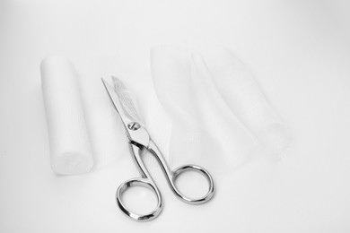 Photo of Medical cotton bandage and scissors on white background