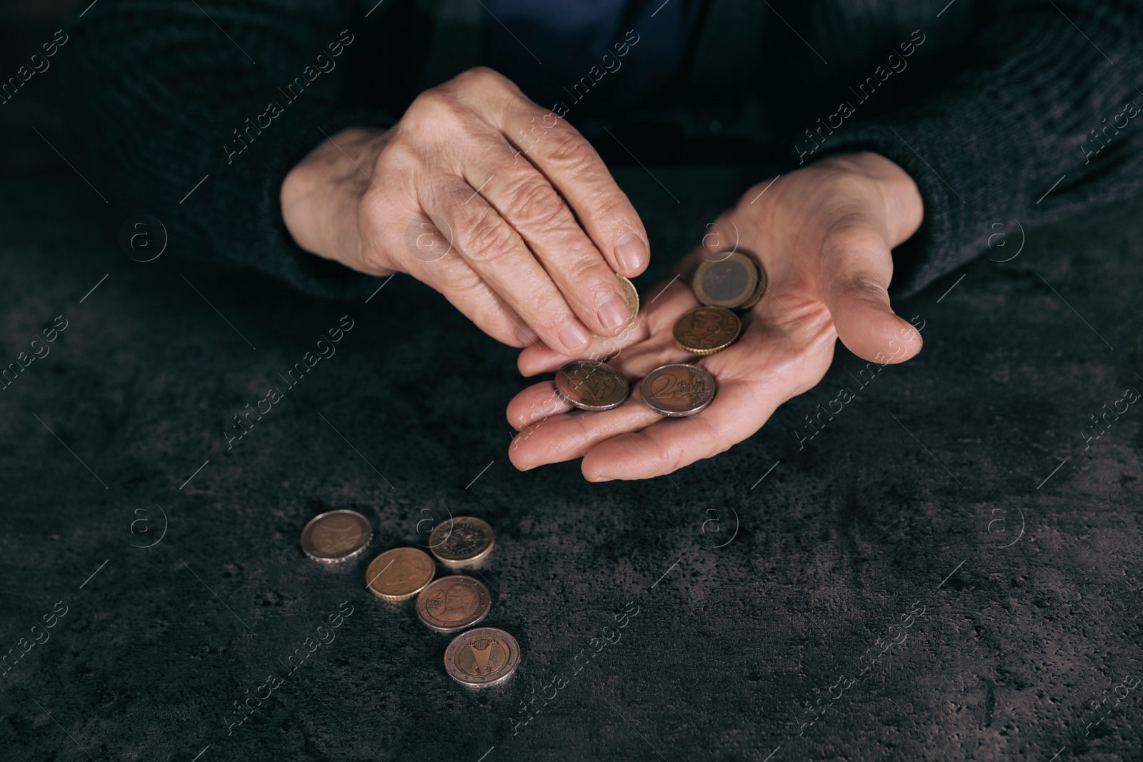 Photo of Poor mature woman counting coins at table, closeup