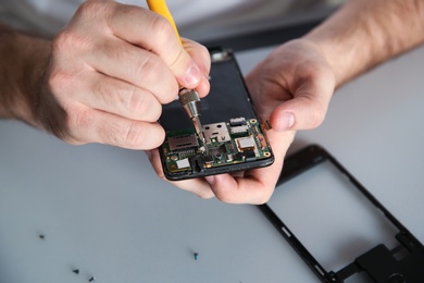 Photo of Technician repairing mobile phone at table, closeup