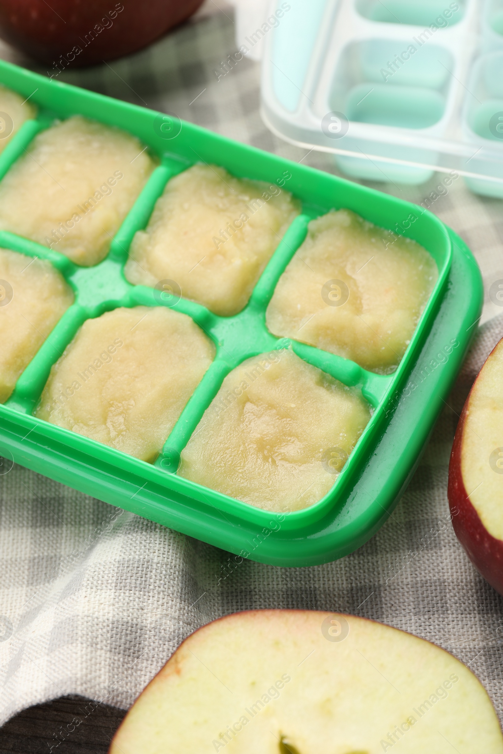 Photo of Apple puree in ice cube tray with ingredients on table, closeup