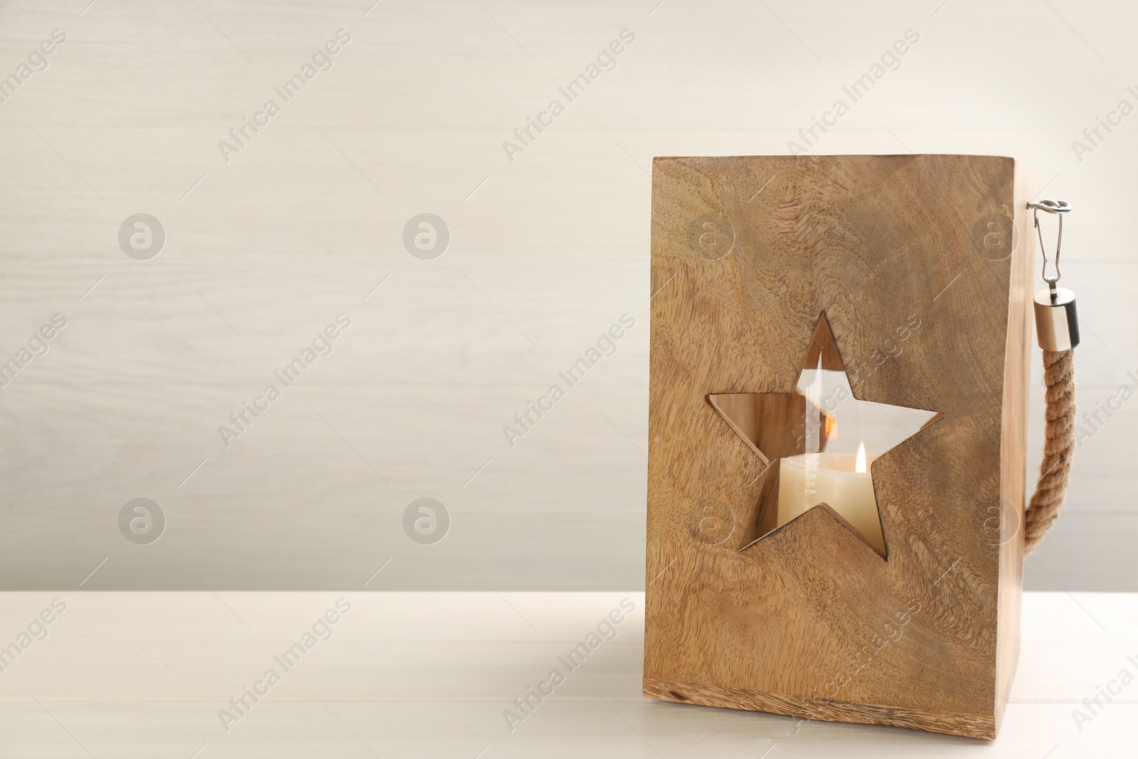 Photo of Beautiful decorative Christmas lantern with burning candle on white wooden table. Space for text