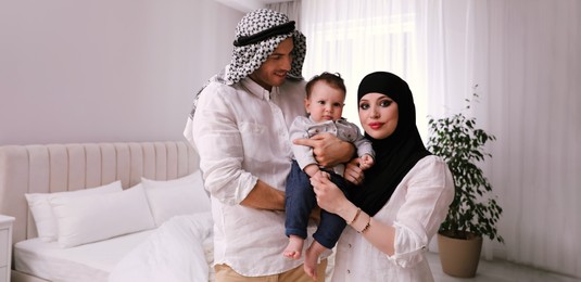 Happy Muslim family with little son in bedroom. Banner design 