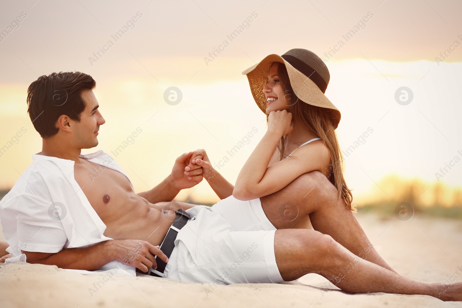 Photo of Happy young couple relaxing together on sea beach at sunset