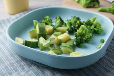 Photo of Pieces of boiled broccoli and squash on grey table. Child's food