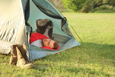 Photo of Young man resting in sleeping bag inside camping tent