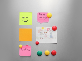 Photo of Paper sheets, child's drawing and magnets on refrigerator door