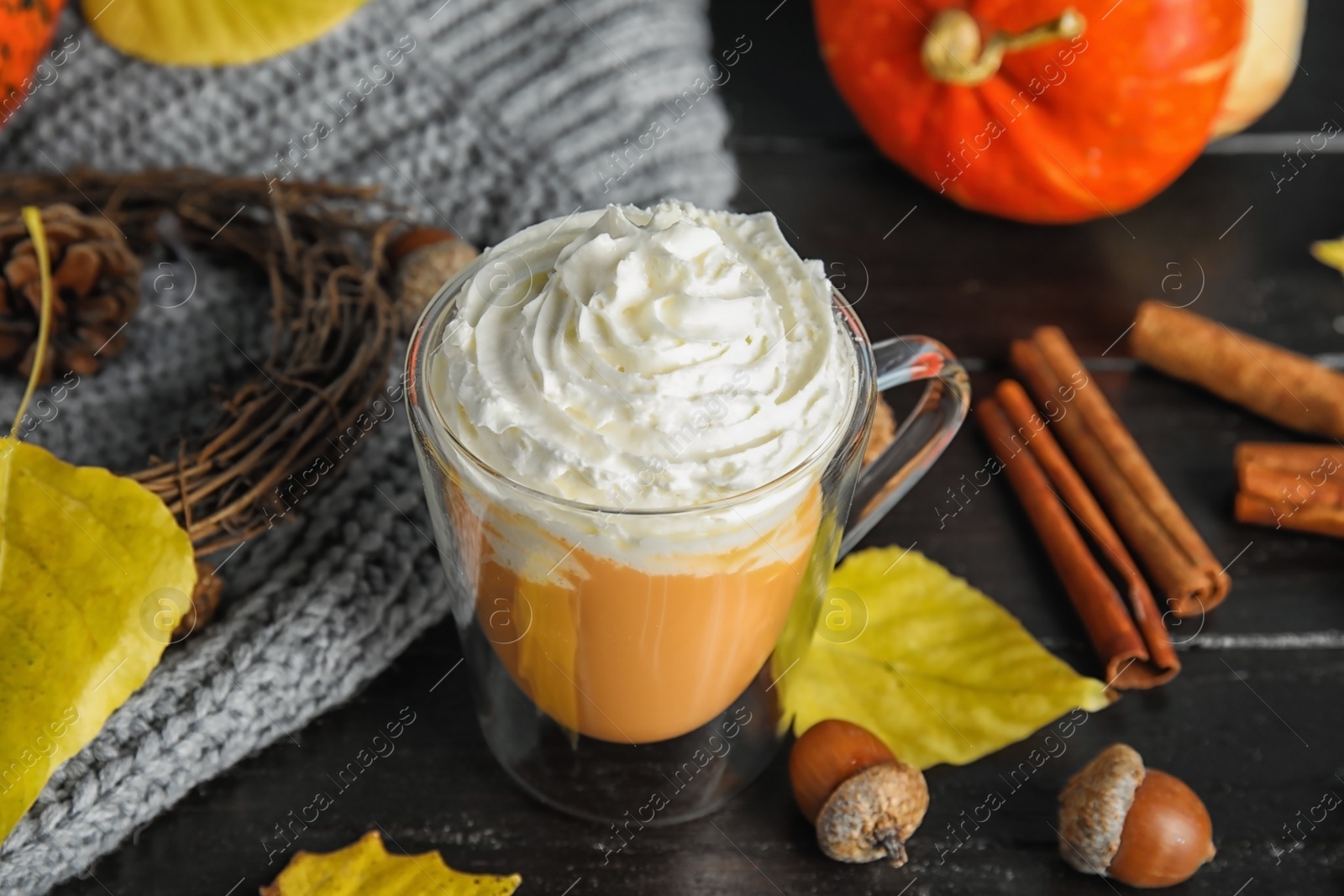 Photo of Composition with tasty pumpkin spice latte in glass cup on table