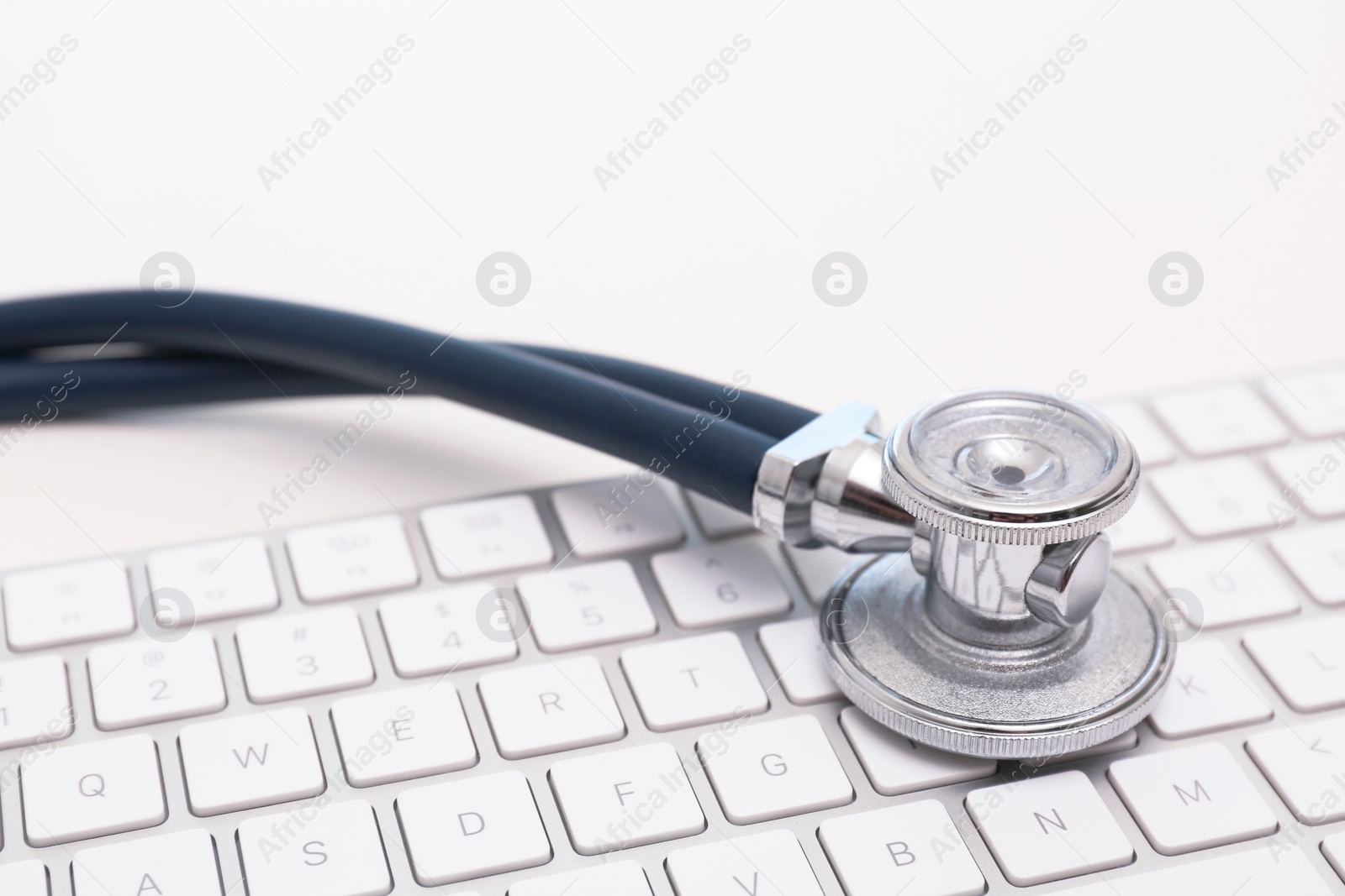 Photo of Modern keyboard and stethoscope on light background. Technical support concept