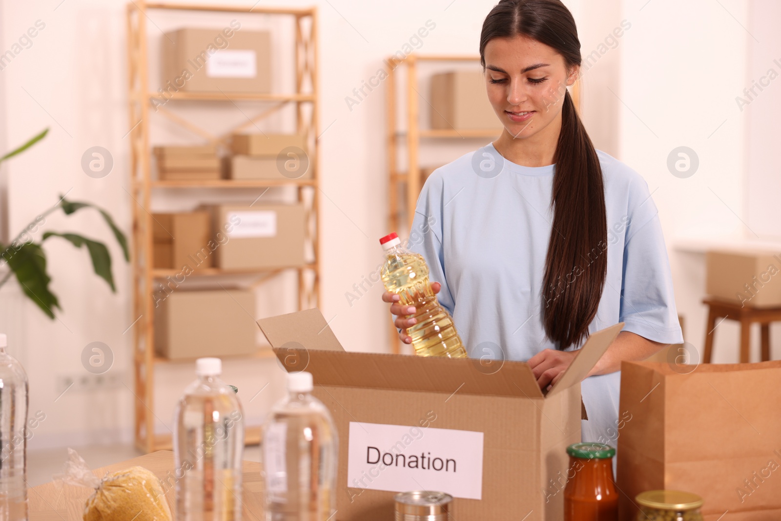 Photo of Volunteer packing food products at table in warehouse