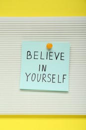 Photo of Note with phrase Believe In Yourself on yellow background, top view. Motivational quote