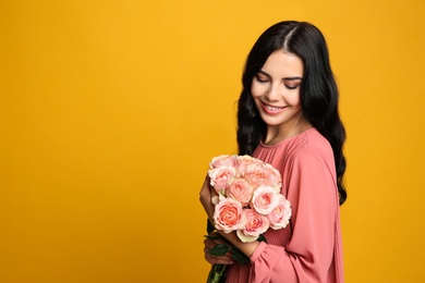 Photo of Portrait of smiling woman with beautiful bouquet on orange background. Space for text